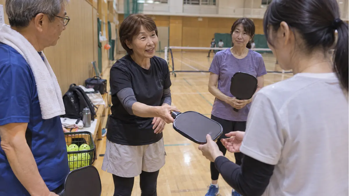 体育館の練習会で初心者にパドルを手渡す参加者