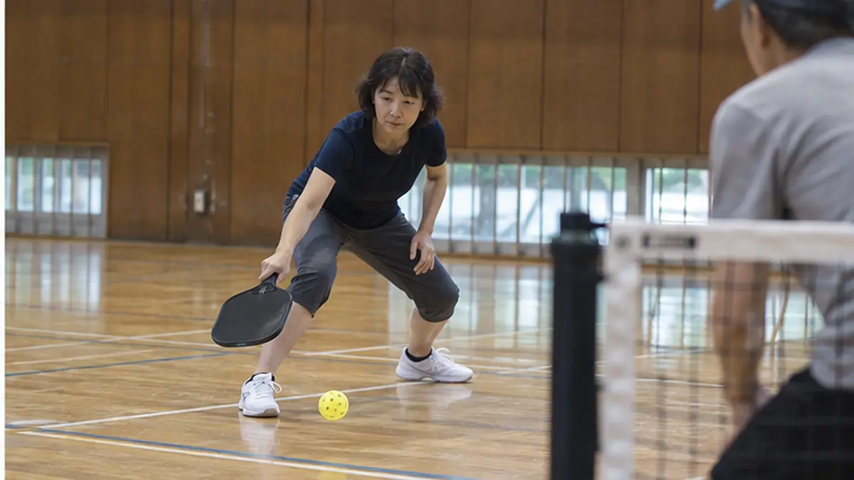 サーブ後のボールをワンバウンドさせて返球する女性