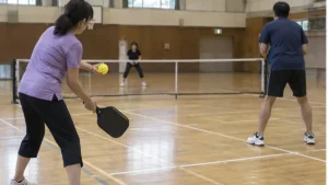 市民体育館でサーブを迎えるピックルボールのダブルス選手