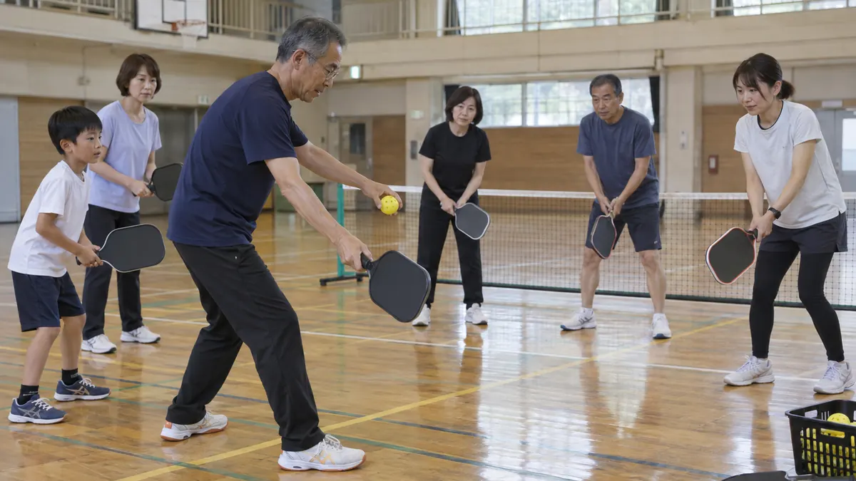 市民体育館で指導者の実演を見ながらパドルを構える親子と初心者