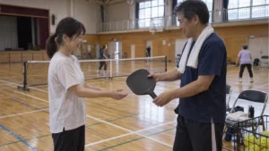 体育館で初心者にグラファイトパドルを手渡すクラブスタッフ