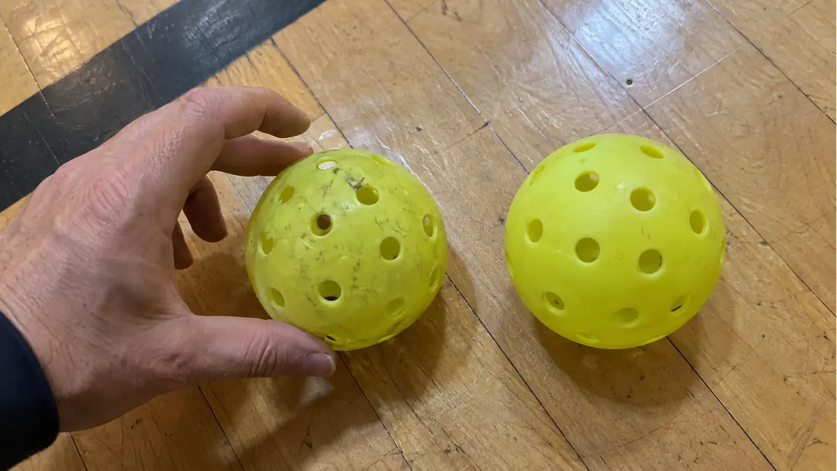 体育館の床で変形したボールと新しいボールを転がして比べる様子