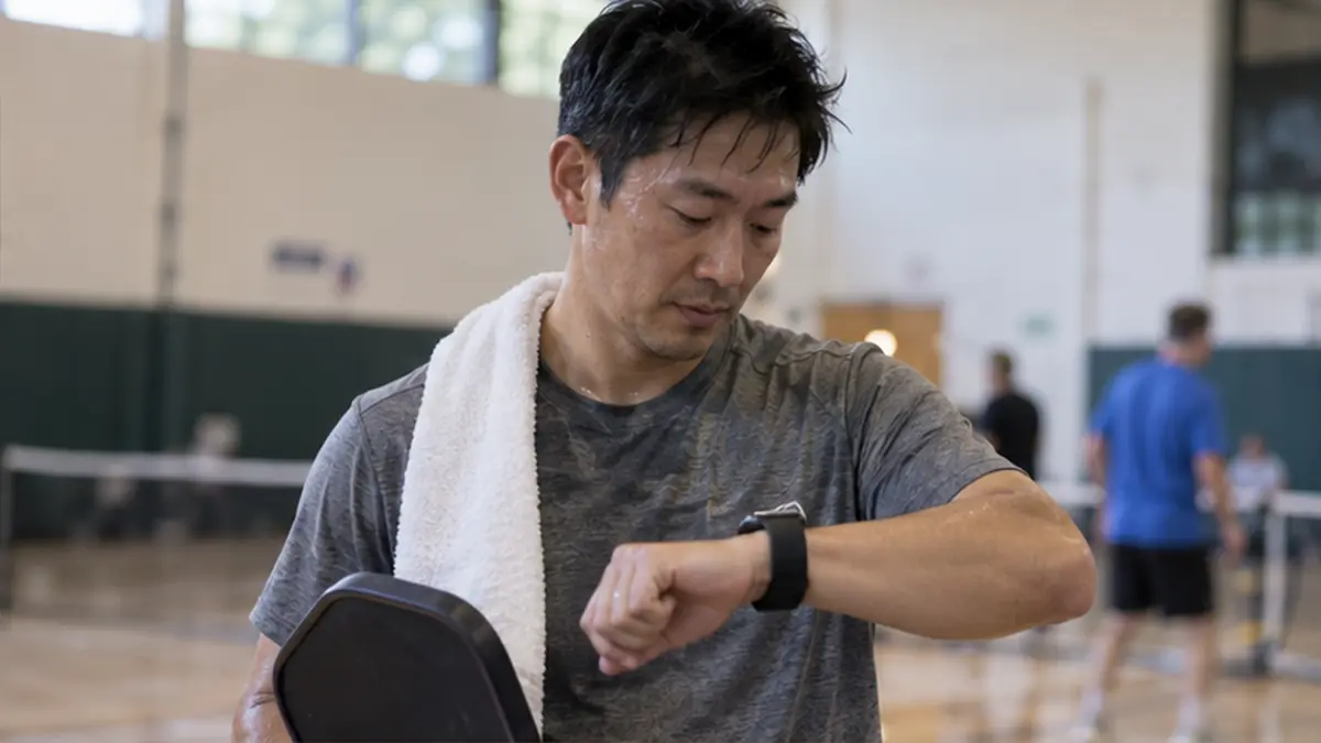 試合後にパドルを持ちながら腕時計を確認する男性