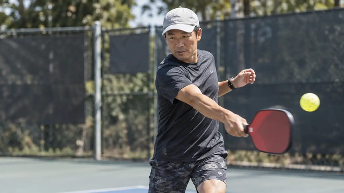 赤と黒のパドルでフォアハンドを打つ選手