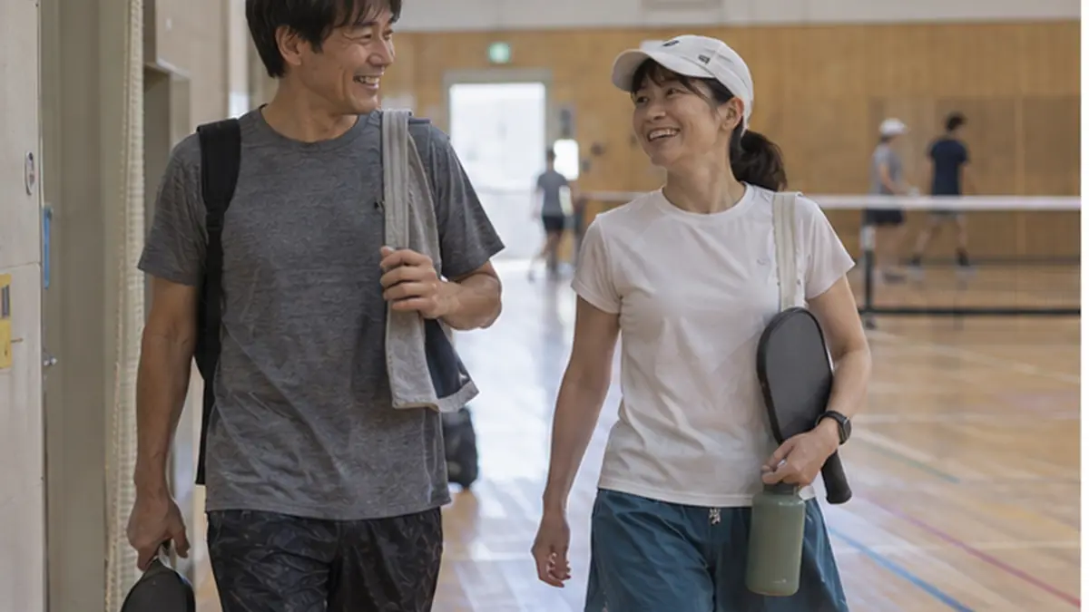 パドルを持って会話しながらコートを離れる男女