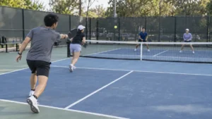 深いリターンを返してキッチンラインへ進むダブルス選手