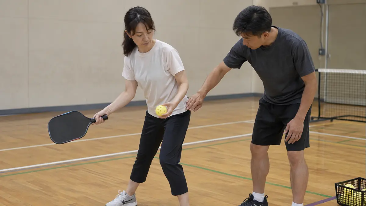 体育館でサーブの打点とフォームを確認するプレーヤーとコーチ