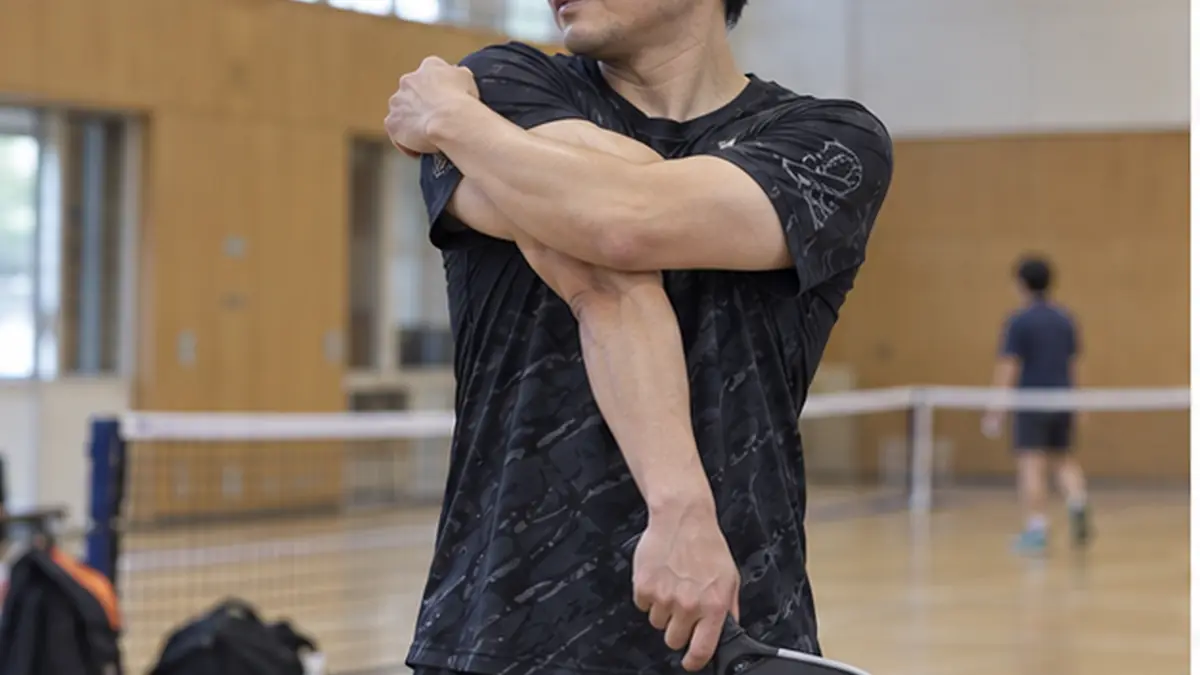 プレー後にパドルを持ちながら肩と腕を伸ばす男性