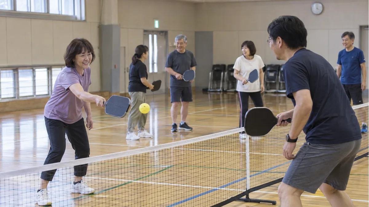 市民体育館で初対面の参加者がゆっくりラリーを始める様子