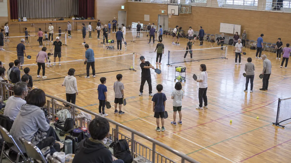 市民体育館の複数コートで練習する親子と高齢参加者
