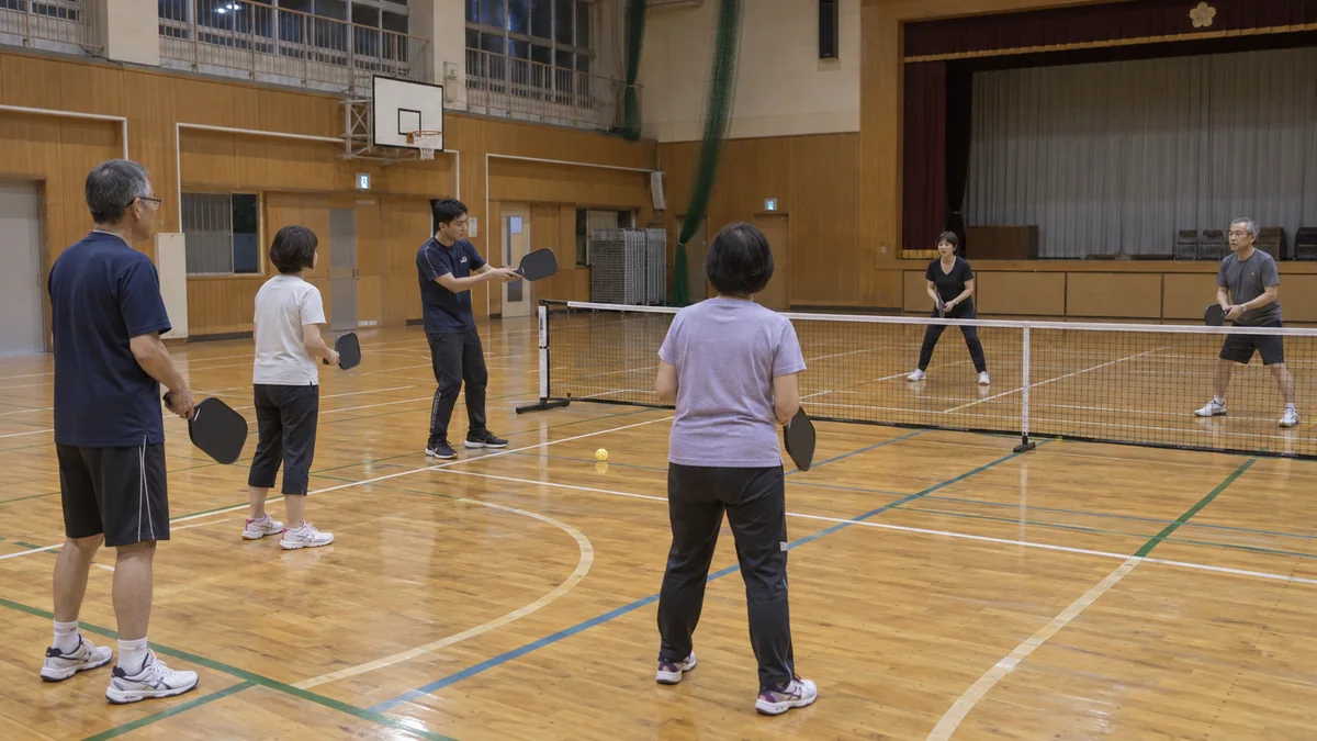公共体育館でピックルボールの基本を教わる地域の参加者